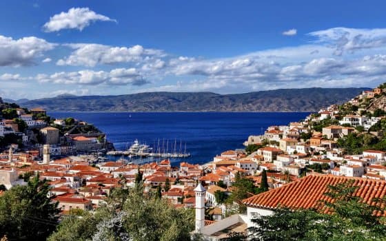 Scenic harbor of Hydra island with red-tiled houses and yachts