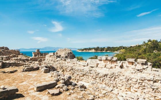 Ancient stone ruins overlooking turquoise sea in Greece